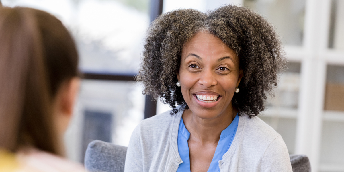 A Black woman smiles as she helps a client.